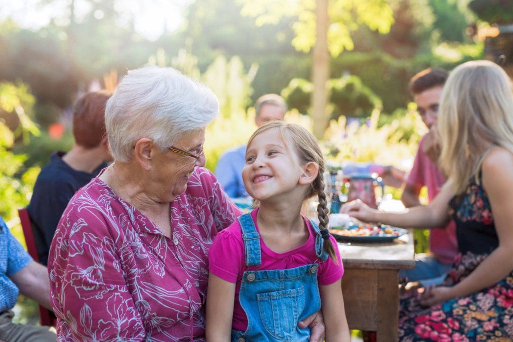 A grandmother with her grandaughter on her lap at a family picnic